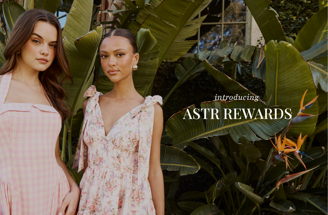 Two women in pink dresses standing in a tropical garden, with text reading 'introducing ASTR REWARDS'