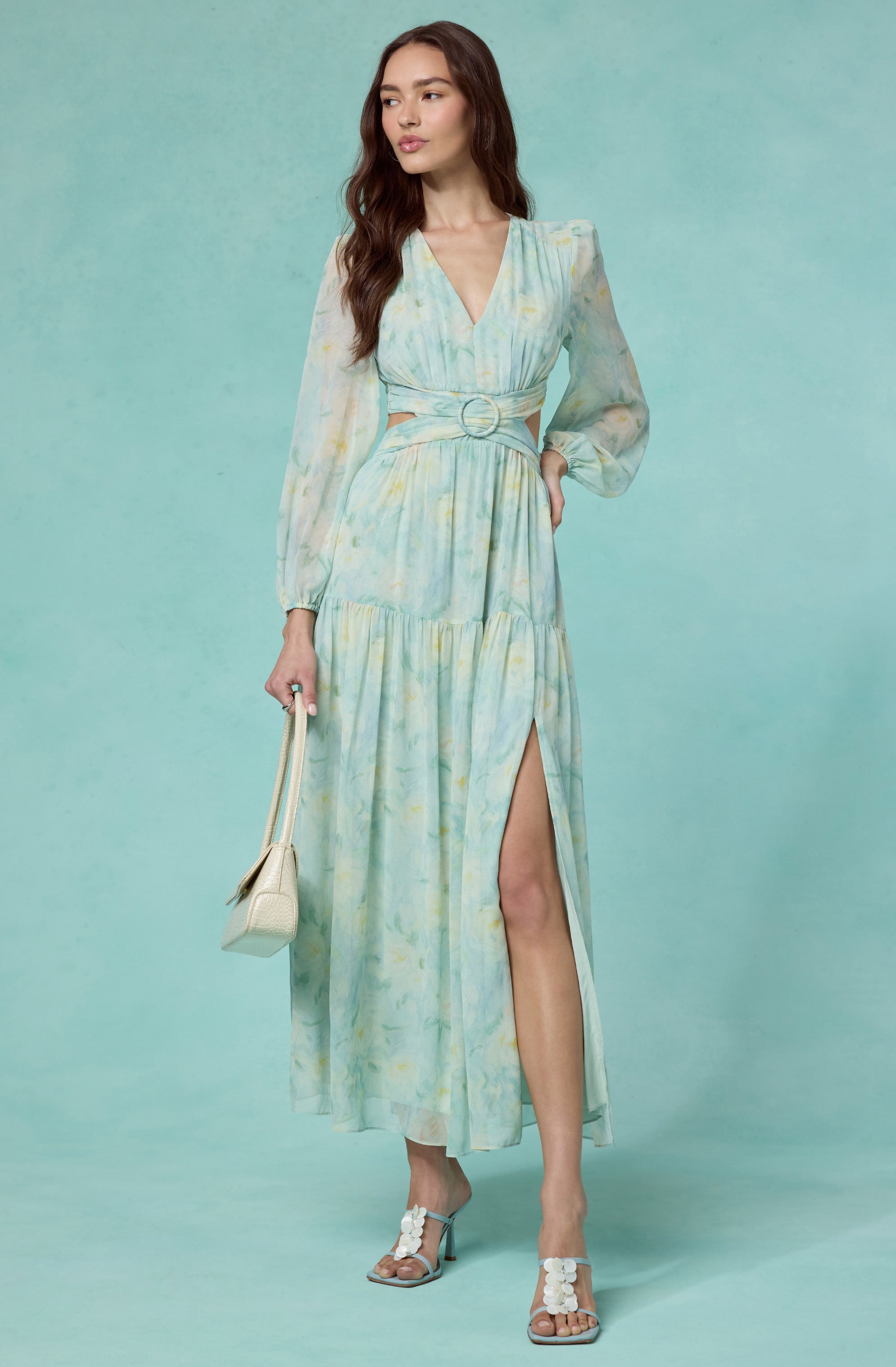 Long pastel-colored dress with long sheer sleeves, a side slit, and a belt.