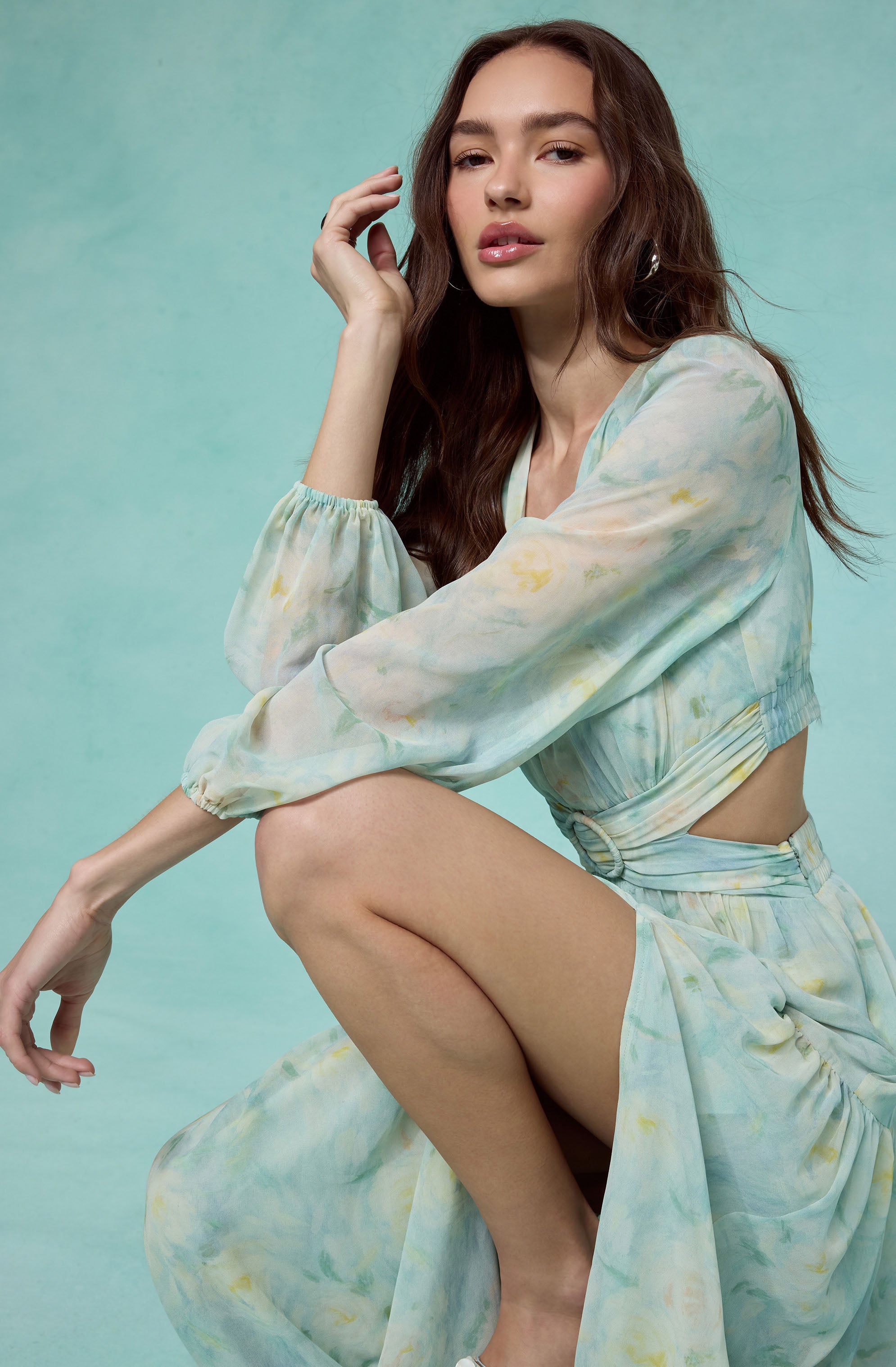 Young woman in a pastel tie-dye two-piece outfit with long, flowy sleeves and a cutout waist.