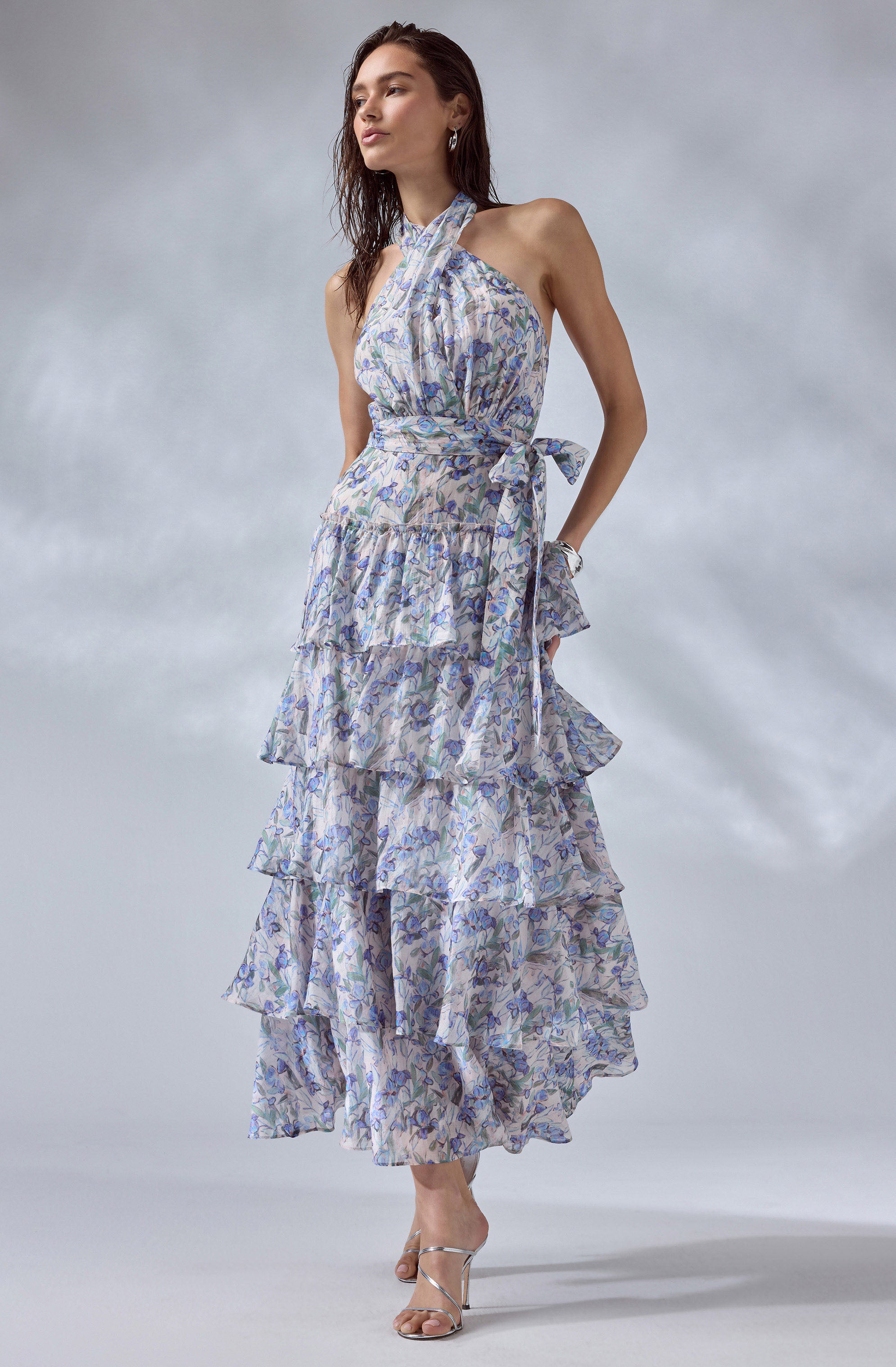 Woman wearing a sleeveless, halter maxi dress with tiered ruffles and a floral pattern.