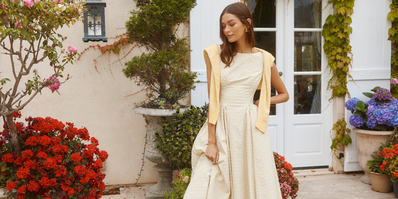 Woman in a cream-colored sleeveless dress with a textured pattern and yellow details.