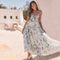 Woman in a blue and white floral maxi dress with ruffled straps, standing outdoors.