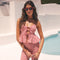 Woman in a pink and white gingham summer outfit with a fitted top and matching pants.