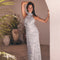 Woman in a sleeveless, high-neck, white dress with floral embellishments and ruffled details.