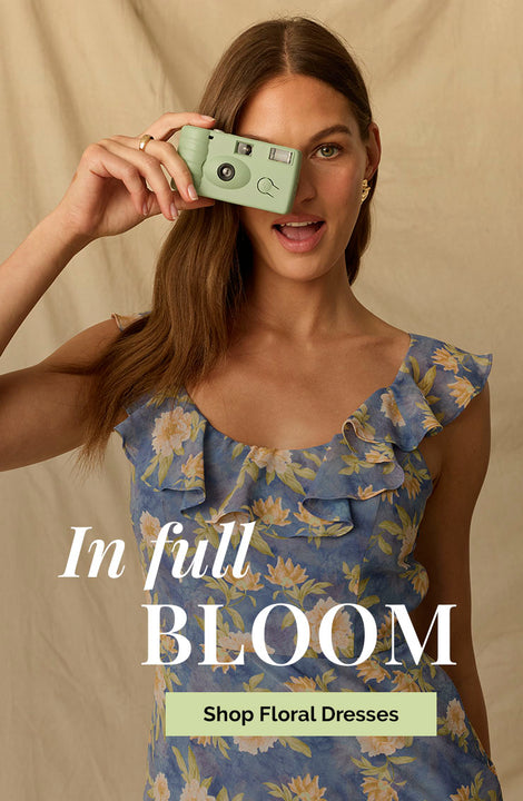 Young woman in a sleeveless blue floral dress with ruffled shoulders.