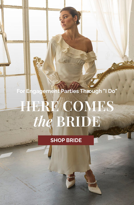 Woman in a cream off-shoulder dress with ruffle details and long sleeves, in a vintage-style room.