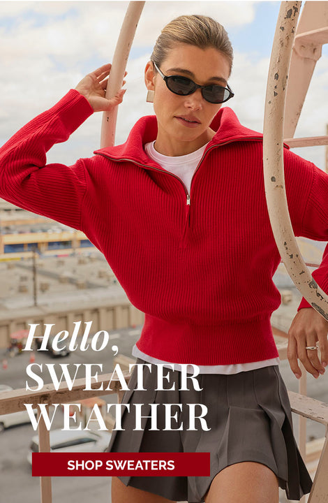 Woman wearing a red ribbed sweater with a half-zip collar and dark sunglasses.