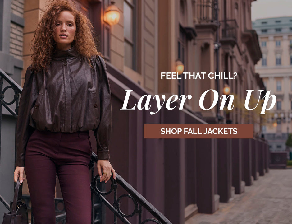 Woman in a shiny dark brown fall jacket and maroon pants on city stairs.