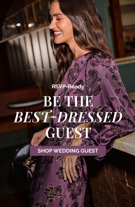 Woman in purple floral satin dress smiling indoors.