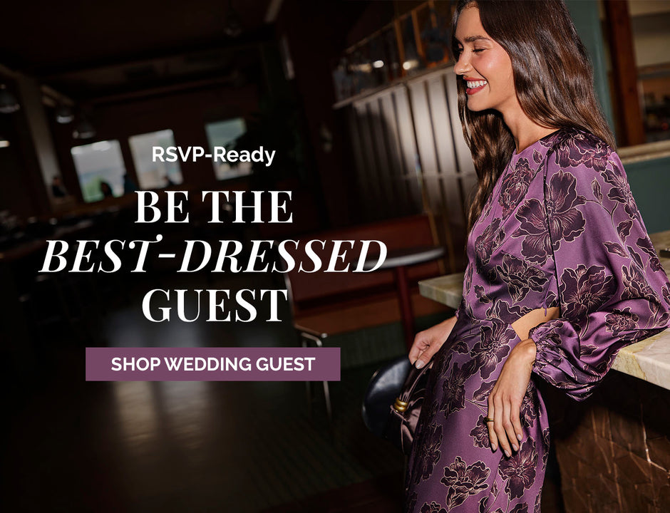 Woman in purple satin floral dress smiling in a bar or restaurant setting.