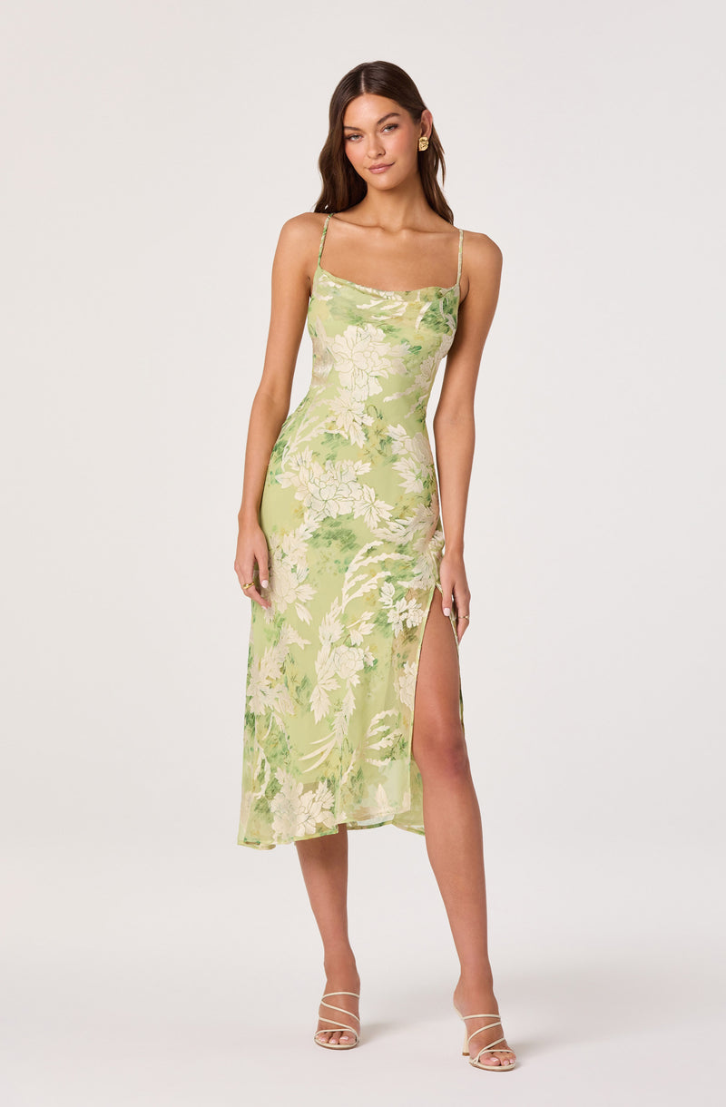 Lady wearing a light green floral slip dress with spaghetti straps and a thigh-high slit.
