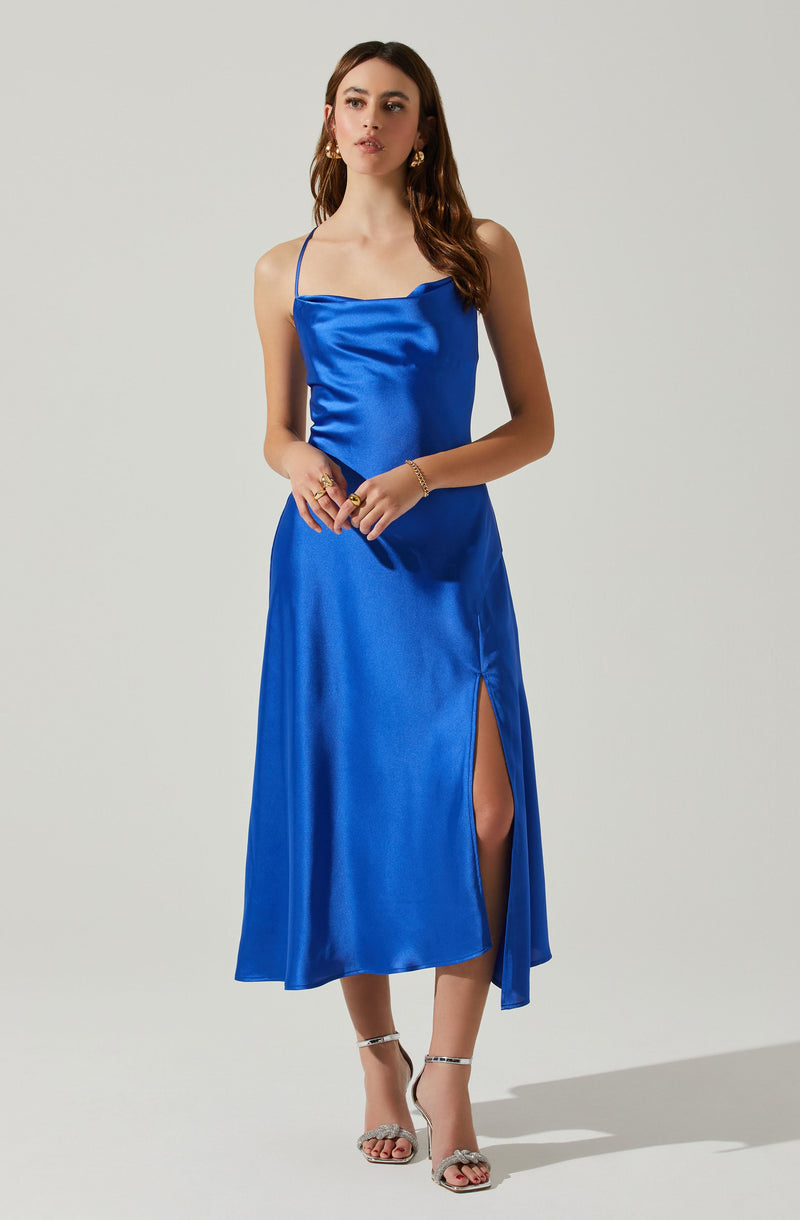 Woman wearing a royal blue satin dress with spaghetti straps and a side slit.