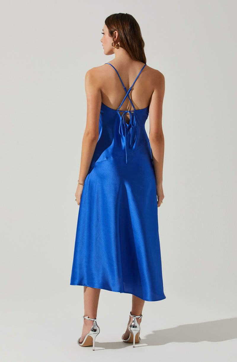 Back view of a woman wearing a shiny cobalt blue satin slip dress with thin straps and a lace-up back.