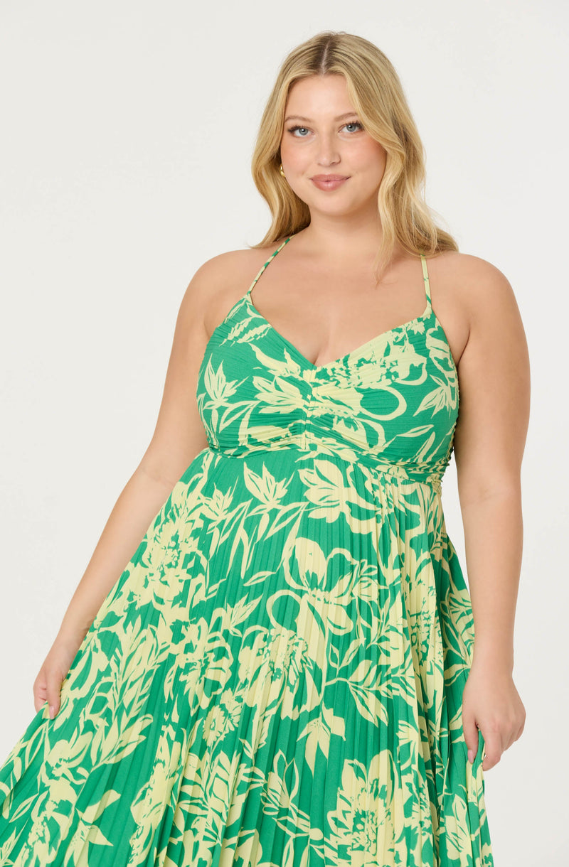 Woman wearing a green and yellow floral spaghetti strap maxi dress.
