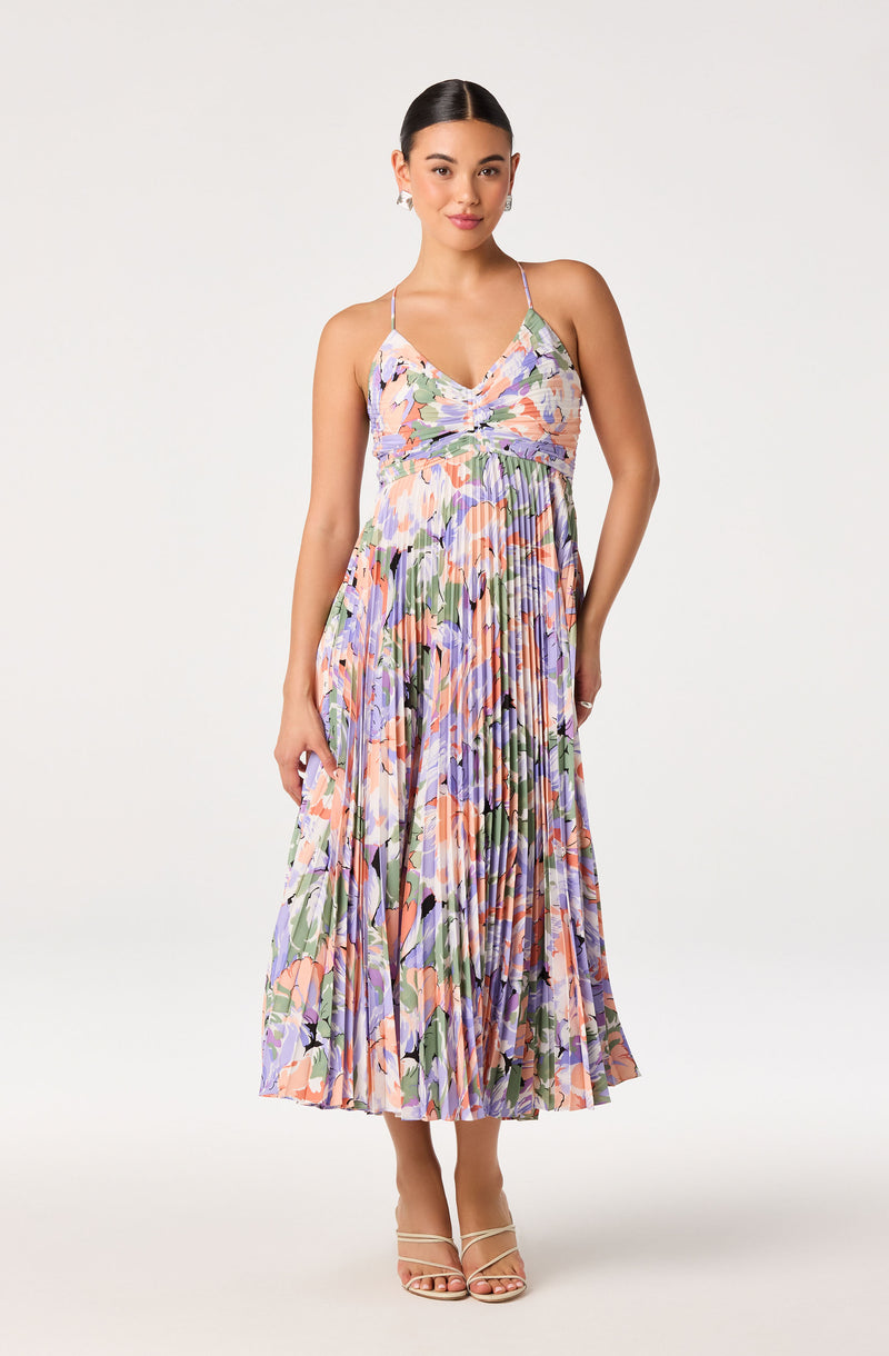 Woman in a floral pleated maxi dress with spaghetti straps.