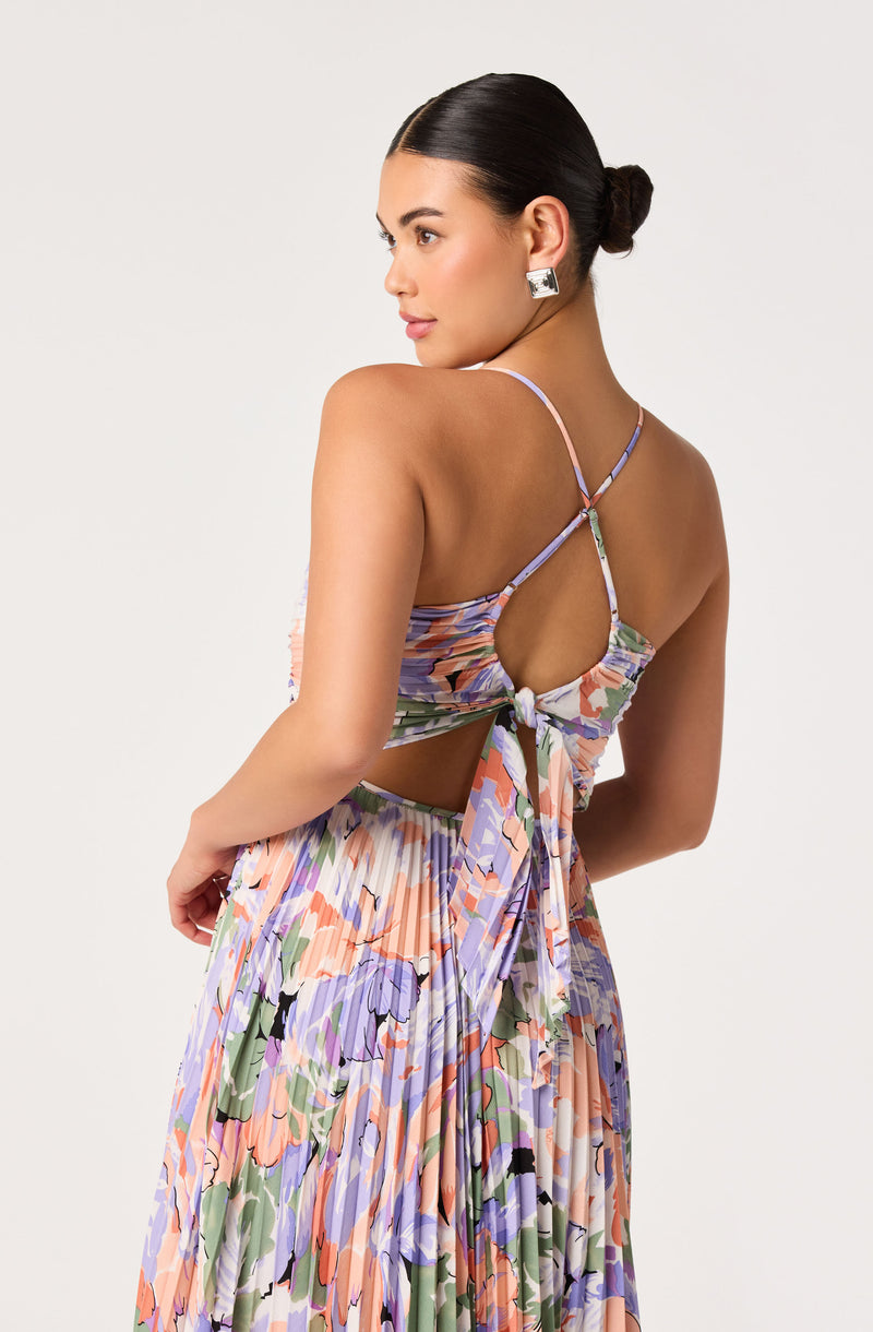 Woman wearing a floral, pleated maxi dress with a cutout back and tied detail.