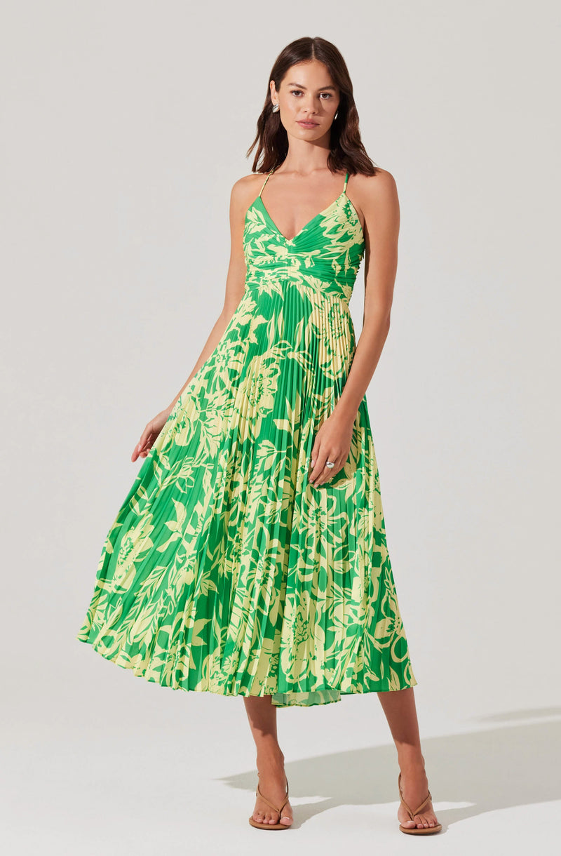 Woman in a green and yellow floral maxi dress with thin spaghetti straps.