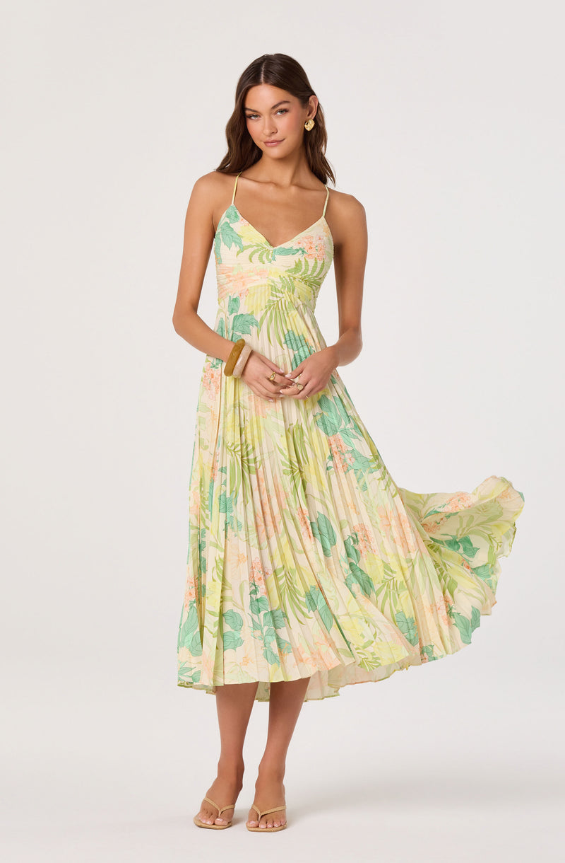 Woman wearing a sleeveless, pastel-colored, floral-printed midi dress with thin straps.