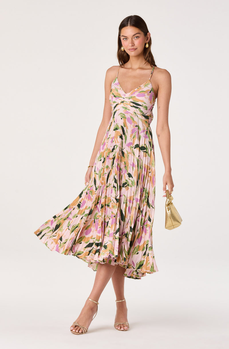 Woman in a pink, green, and beige floral printed midi dress with thin straps.