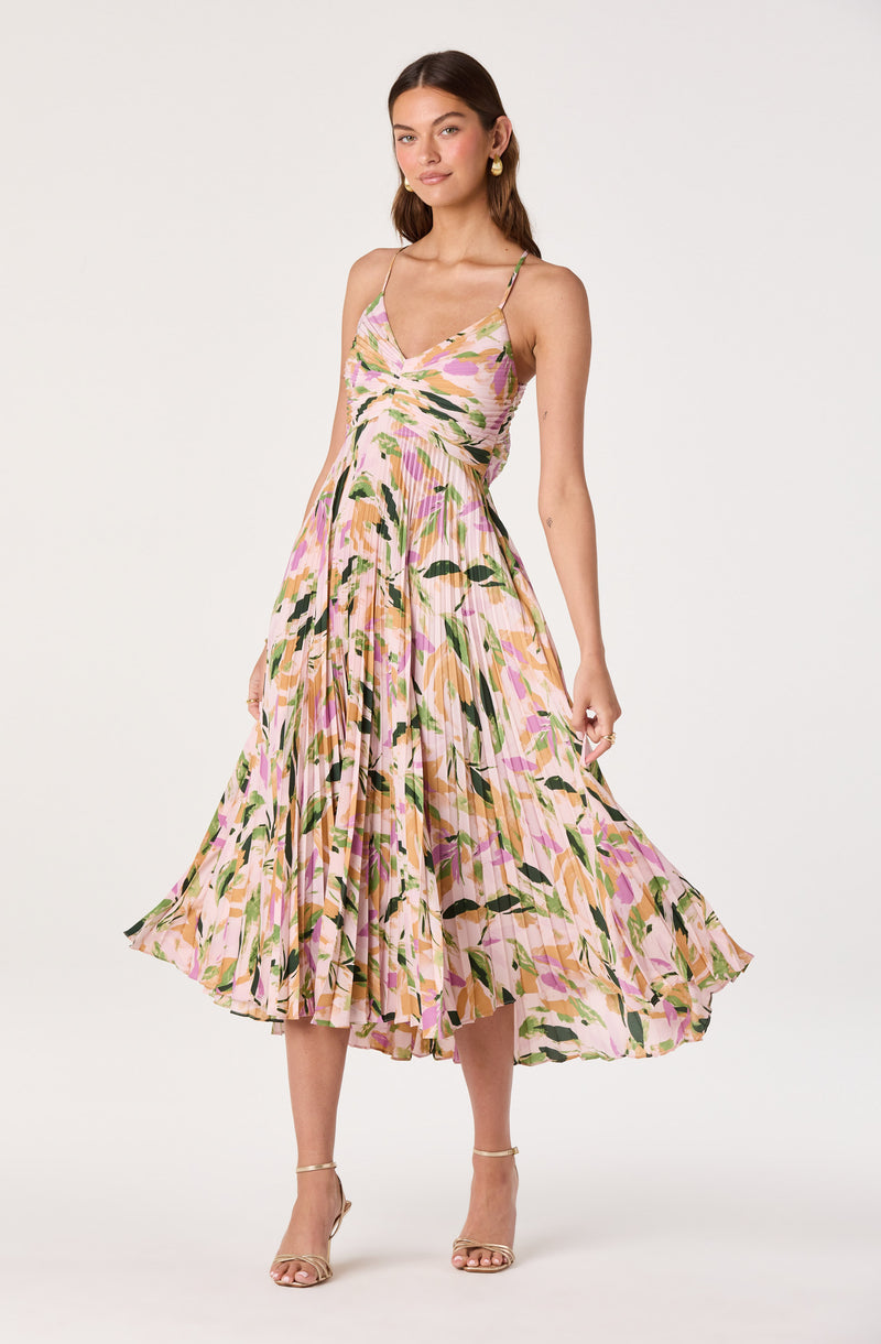 Woman wearing a sleeveless, ankle-length dress with thin straps and a colorful, abstract floral pattern.