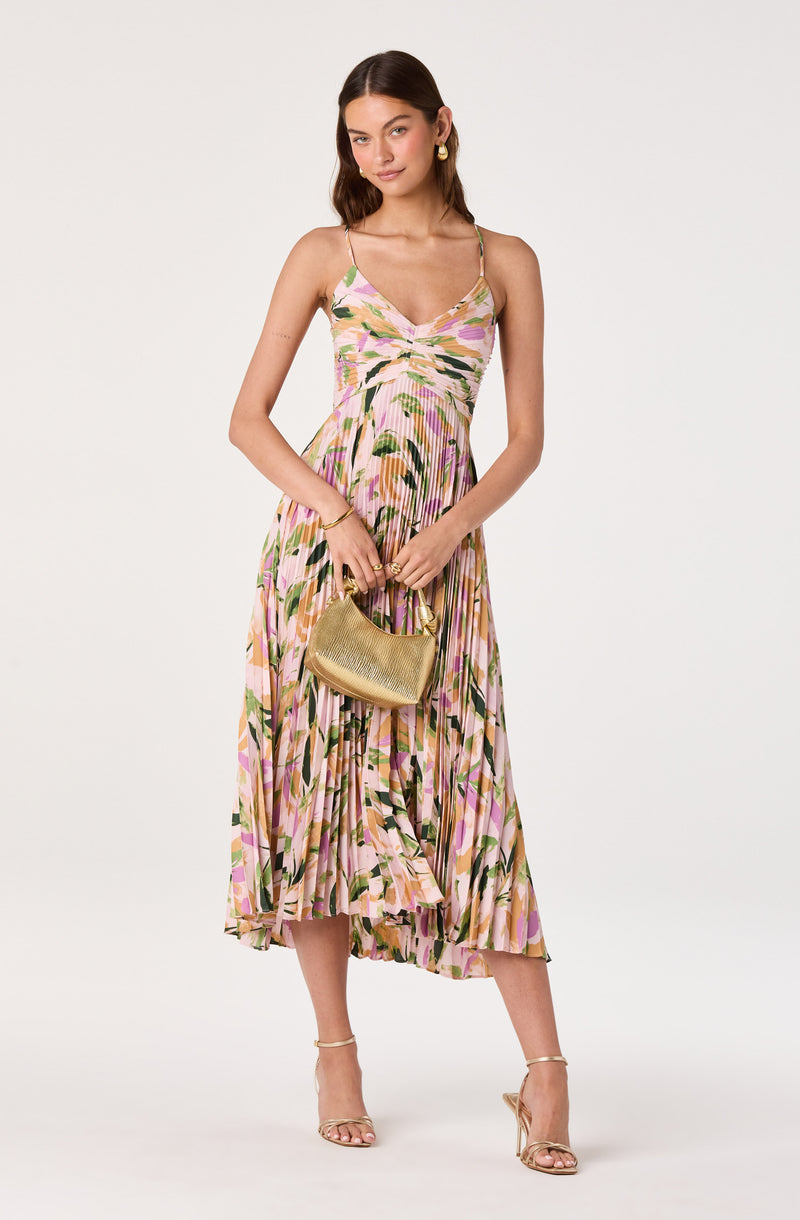 Girl wearing a pink, green, and beige floral printed pleated midi dress with thin shoulder straps.