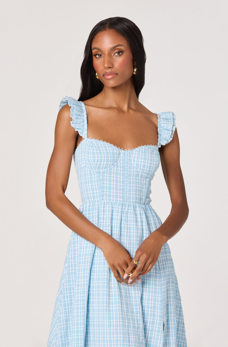 Women in blue and white gingham dress with ruffled shoulder straps and fitted bodice.