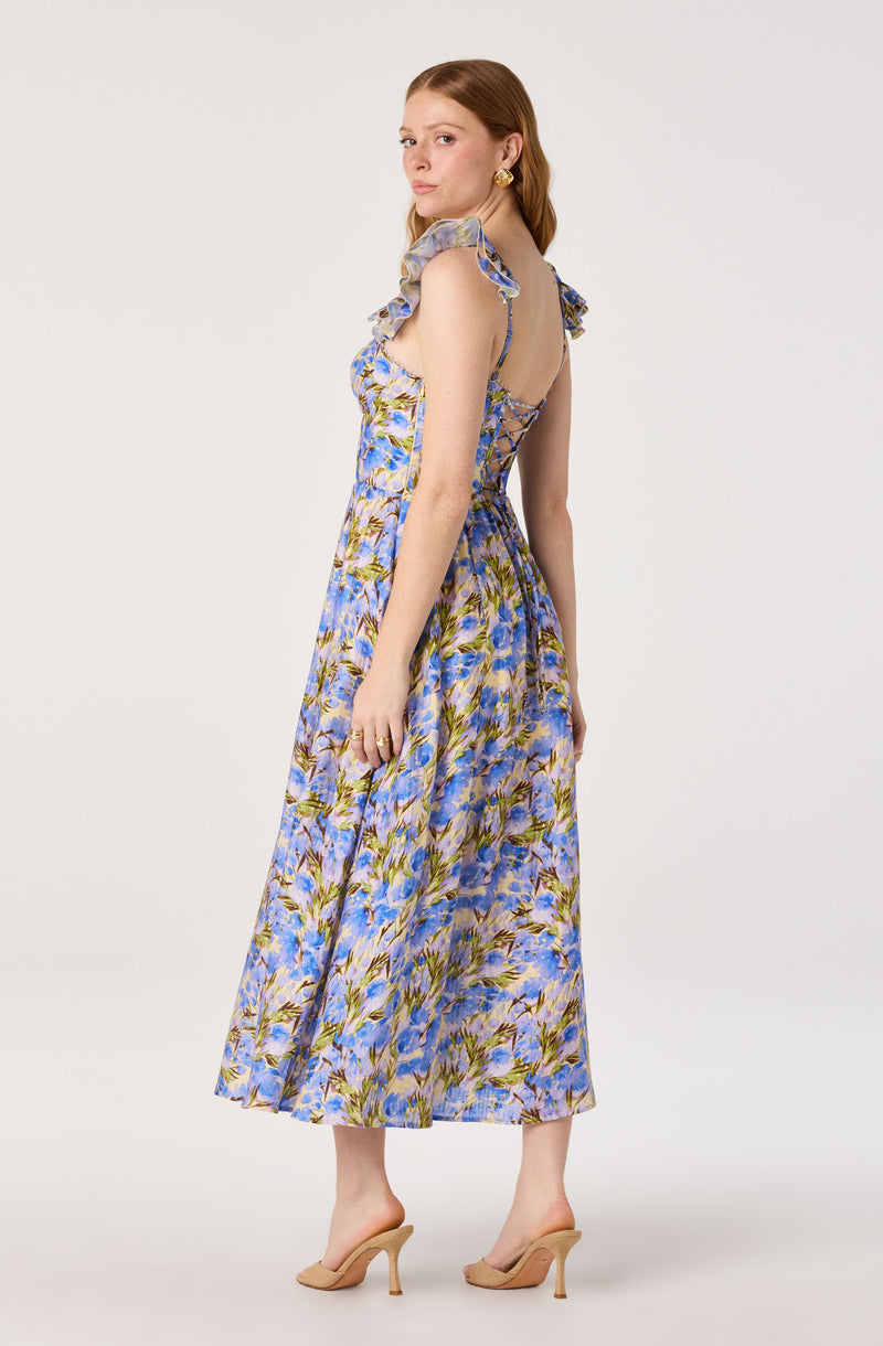 Woman in a sleeveless, floral lavender dress with ruffled shoulders and open back.