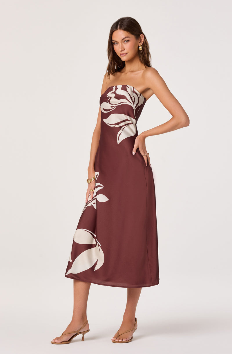 Strapless brown dress with large white floral print, midi length, worn with nude heels.