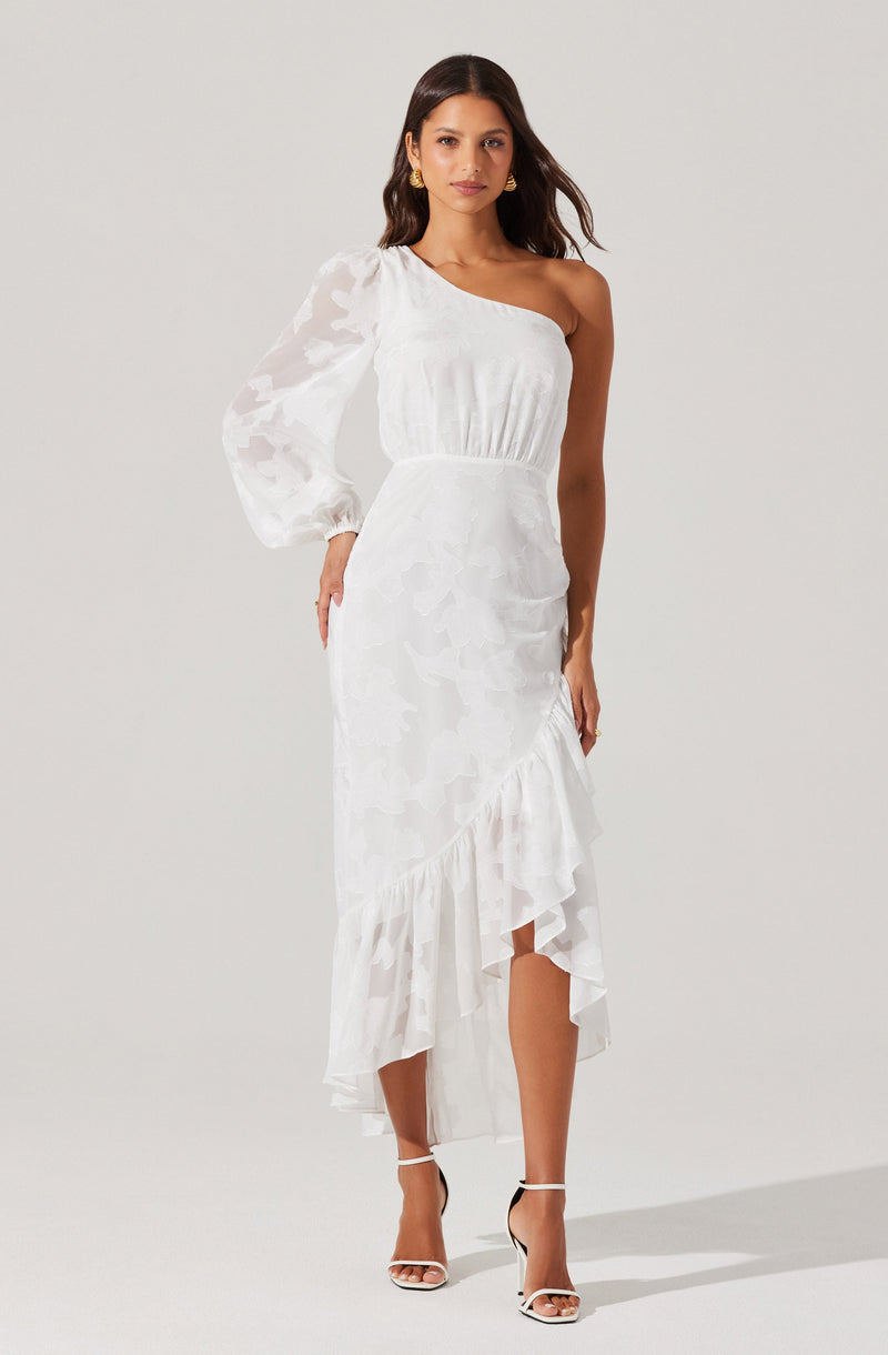 A woman is wearing a white dress with a one-shoulder neckline. The dress features a single long, sheer, puffed sleeve with a subtle floral pattern. The bodice is fitted and gathered at the waist, and the skirt is flowy with a ruffled asymmetrical hemline that falls below the knees.