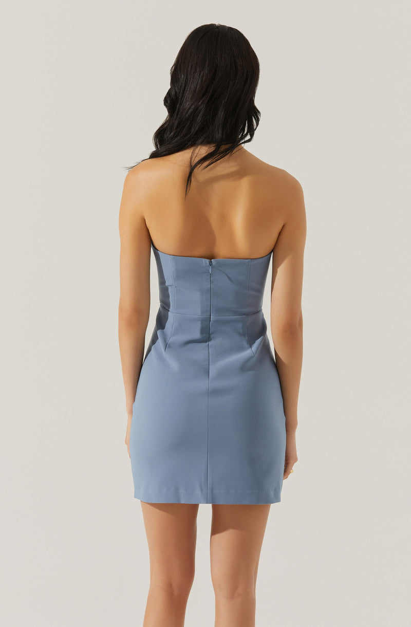A woman is wearing a strapless, light blue, fitted mini dress with a zipper in the back. The dress appears to be made of a smooth, slightly shiny fabric.