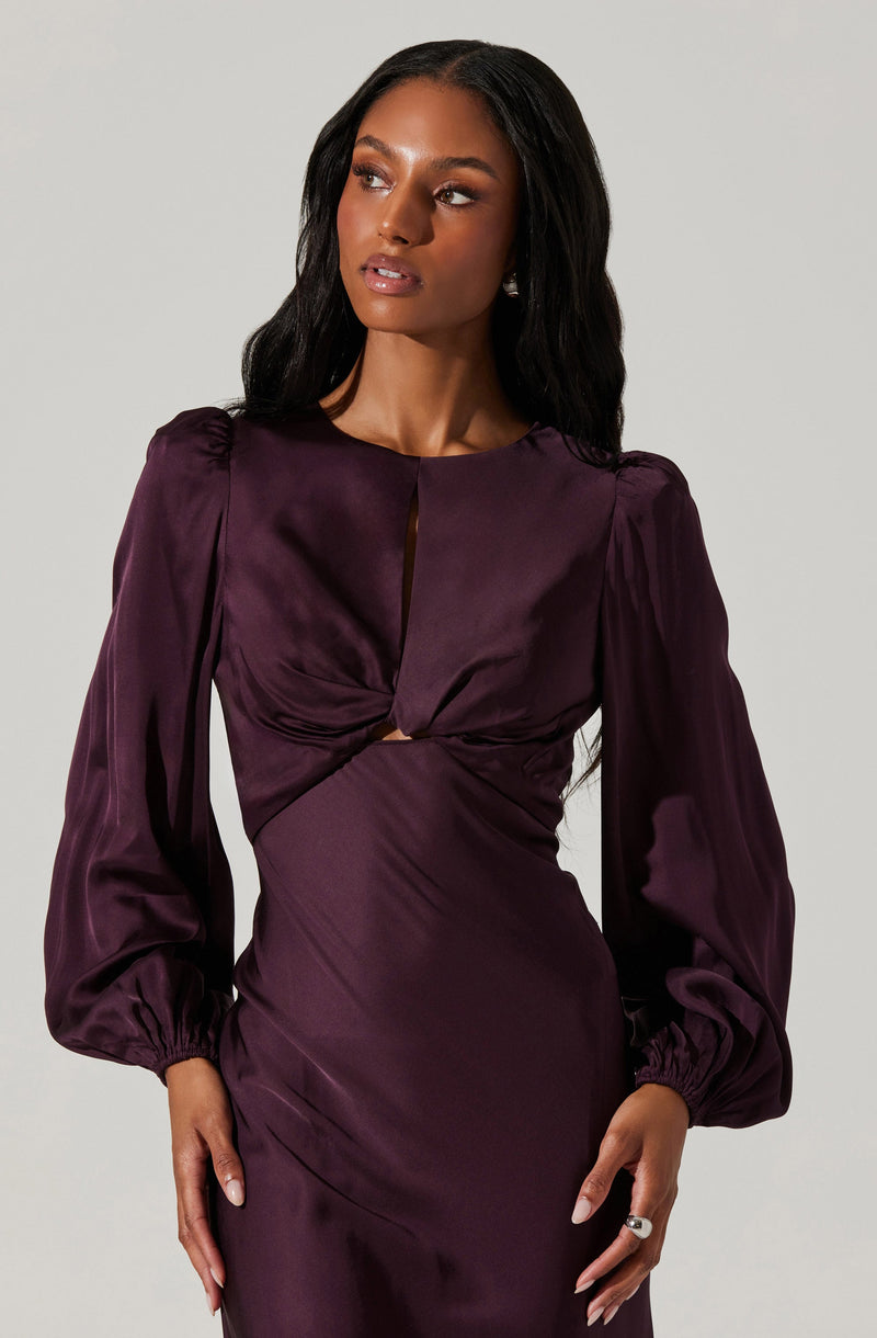 A woman is wearing a dark purple satin dress with long puffed sleeves gathered at the wrists. The dress features a keyhole neckline and a gathered knot detail at the bust, creating a fitted silhouette.