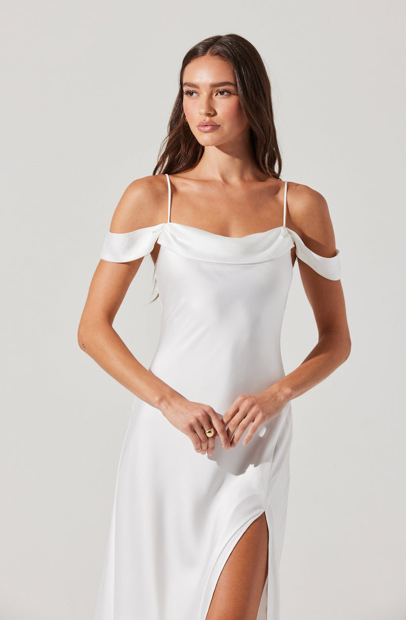 A woman is wearing a white dress with thin spaghetti straps. The dress features off-the-shoulder sleeves that drape over her upper arms, and it has a high slit on the side. The fabric appears to be smooth and shiny.