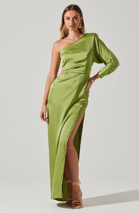 A woman is wearing a shiny, emerald-green satin gown with an asymmetrical, one-shoulder design. The dress features a high slit on the left side, revealing her leg and beige strappy high-heeled sandals. The gown also has a gathered detail around the waist and a puffed long sleeve on her right arm.