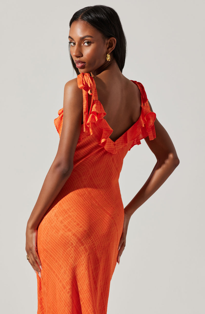 A woman is wearing a bright orange dress with ruffled shoulder straps. The dress has a fitted bodice and a textured fabric pattern.