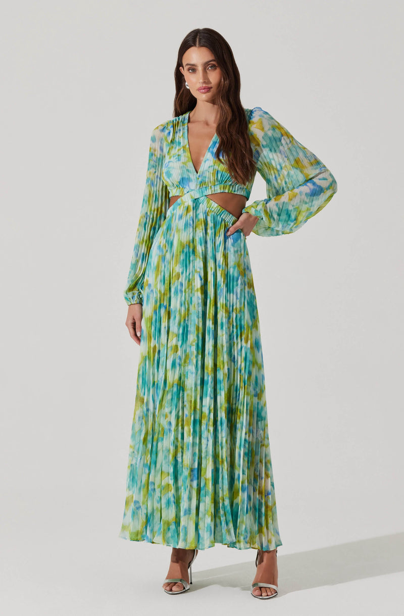 The dress features a vibrant, tie-dye pattern with shades of blue, green, yellow, and white. It has long, slightly puffed sleeves with elastic cuffs, a deep V-neckline, and a cut-out detail at the waist. The skirt is long and flowing, with pleats that add texture and movement. The overall look is colorful and bohemian.