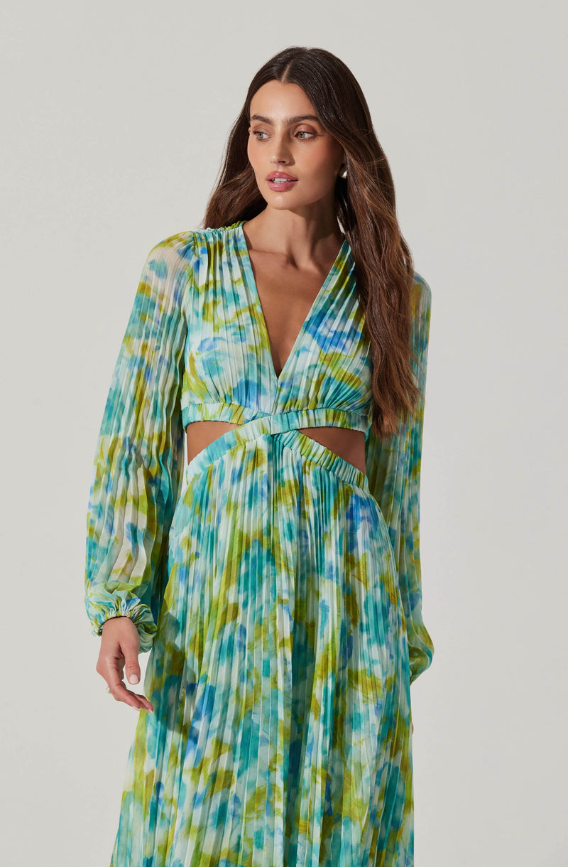 The dress features a deep V-neckline and long, puffed sleeves with elasticated cuffs. The fabric has a vibrant, multicolored abstract pattern in shades of blue, green, and yellow. The dress also includes cut-out sections at the waist and a flowing, pleated skirt.