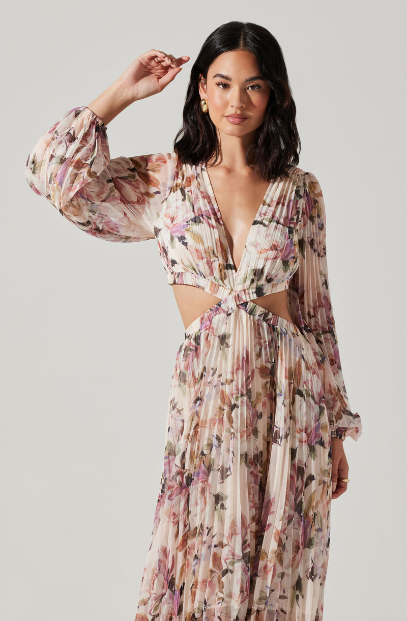 Woman in a floral dress with long, sheer sleeves, deep V neckline, and cut-out waist detail.