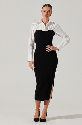 A woman is wearing a white long-sleeved button-up shirt underneath a black, strapless, ribbed knit dress that extends to mid-calf. The dress features a high slit on one side. She is also wearing black high-heeled shoes and gold jewelry, including earrings and rings.