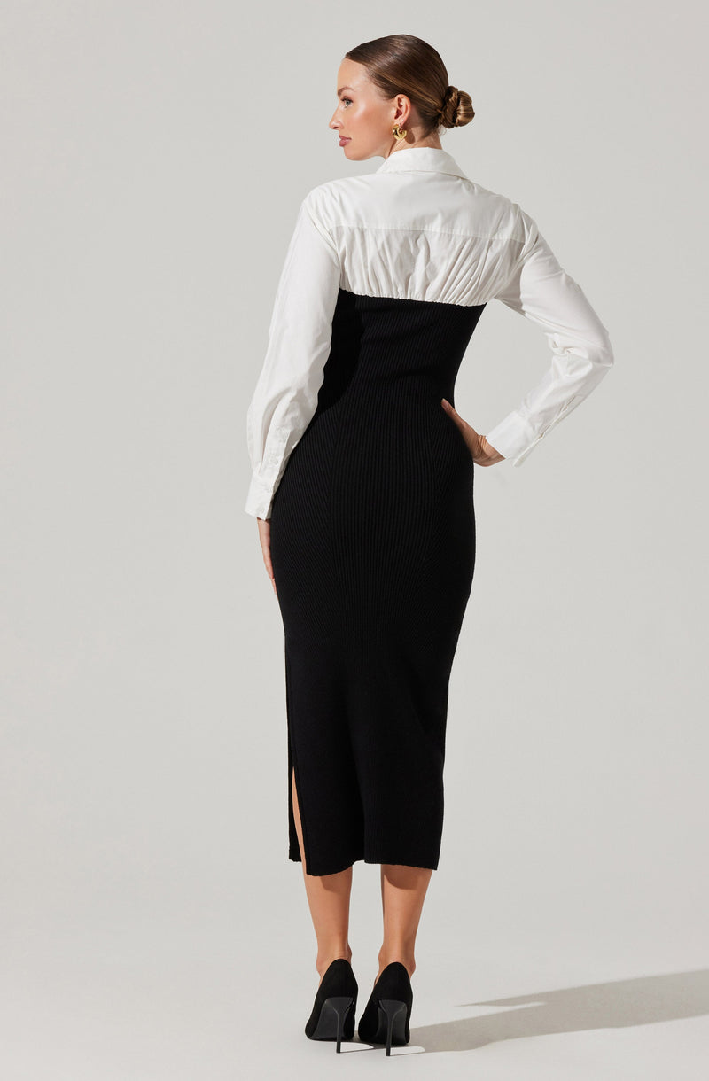 A woman is wearing a two-tone dress featuring a white button-up top with long sleeves and a collar, and a high-waisted, fitted black skirt that extends to mid-calf with a side slit. She is also wearing black high heel shoes.