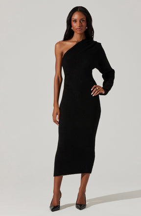 The woman is wearing a black, floor-length, one-shoulder dress with a long sleeve on her right arm and no sleeve on her left arm. She has paired the dress with black high-heeled shoes.