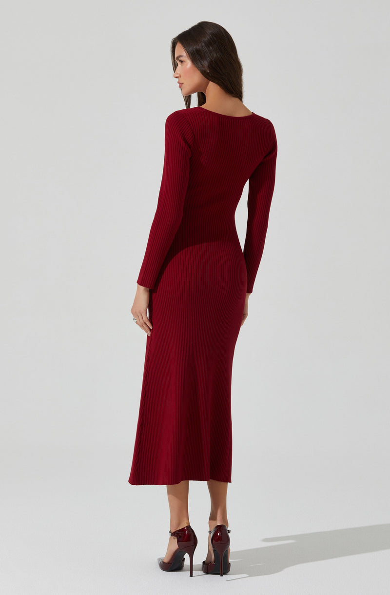 A woman is wearing a fitted, long-sleeved, ribbed knit dress in a deep red color that extends to her ankles. She is also wearing matching high-heeled shoes in a similar shade of red.