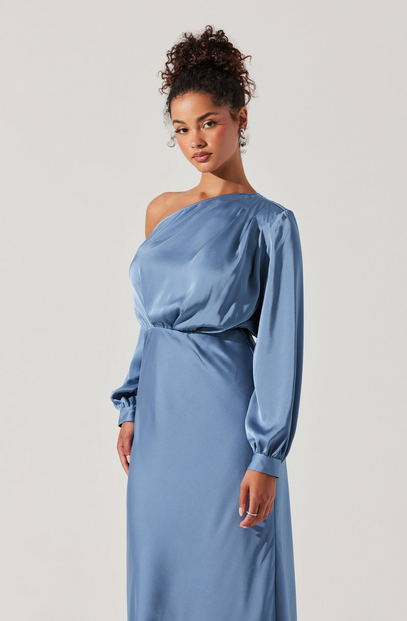 A woman is wearing a light blue satin dress with an asymmetrical one-shoulder design. The dress features long puffed sleeves with elastic cuffs and a fitted waist, flowing down into a long, elegant skirt. The shiny satin fabric gives the dress a smooth and luxurious appearance.