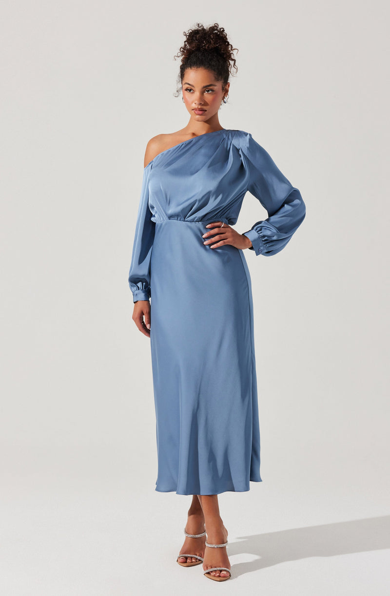 A woman is wearing a long, sky blue satin dress with one shoulder off-the-shoulder design. The dress has a gathered bust and voluminous, puffed long sleeves that are cinched at the wrists with elastic. The waist is fitted, and the skirt flows down to the floor with a slight flare. She is also wearing strappy high-heeled sandals.