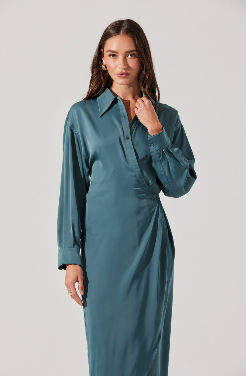 A woman is wearing a teal satin shirt dress with a pointed collar, long gathered sleeves with buttoned cuffs, and a button-down front. The material appears smooth and shiny, giving it a luxurious look.