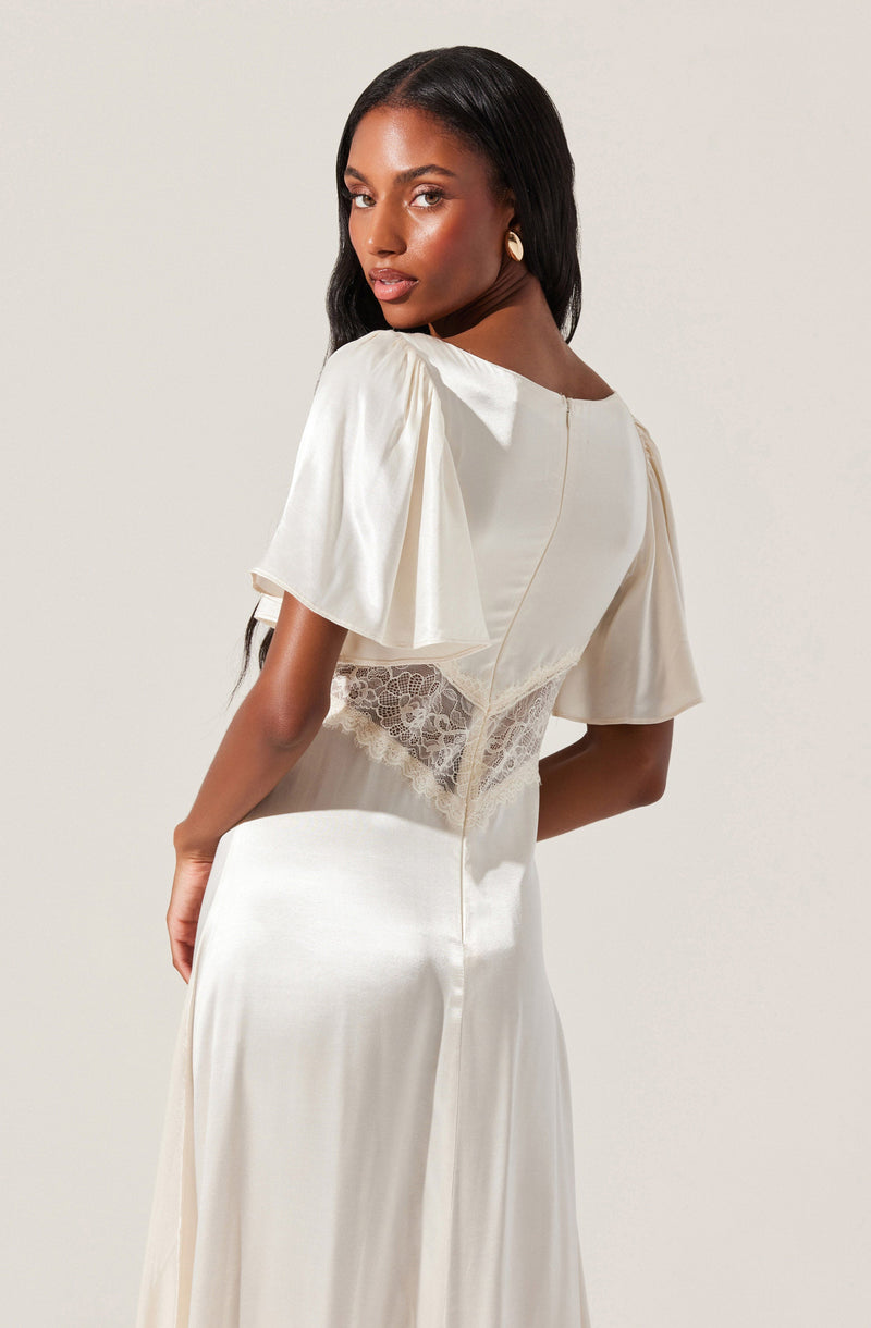 A woman is wearing an elegant, cream-colored satin dress with short, puffed sleeves. The dress features a lace panel at the waist, adding a delicate and intricate detail. The fabric appears smooth and shiny, creating a sophisticated look.