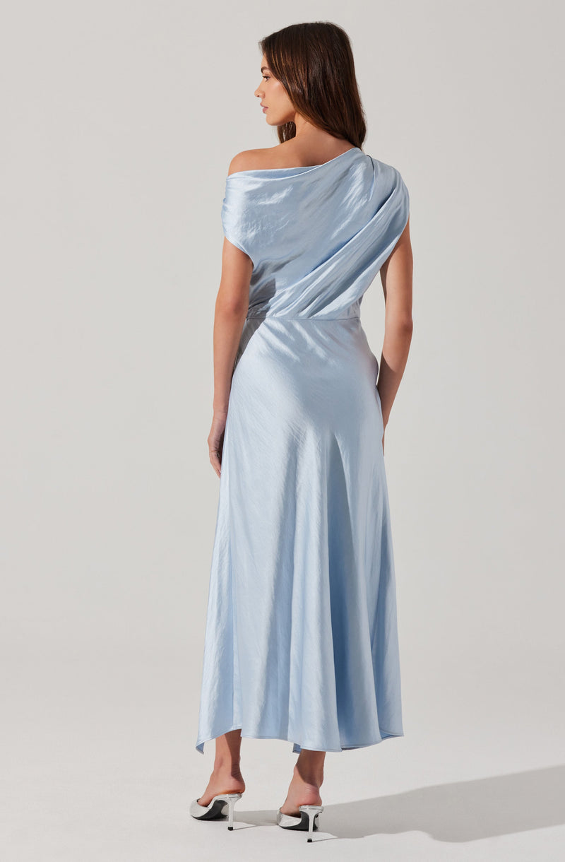 A woman is wearing a silky, light blue, off-the-shoulder dress with a draped design. The dress extends down to her ankles and has a flowing, satin-like texture. She is also wearing white high-heeled shoes.