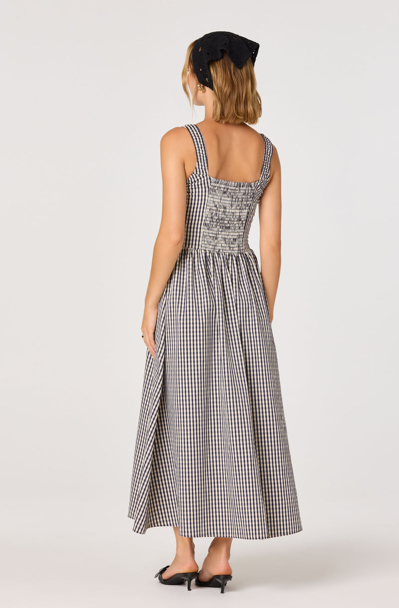 Woman in a long, sleeveless, checkered dress with smocked bodice and wide straps.