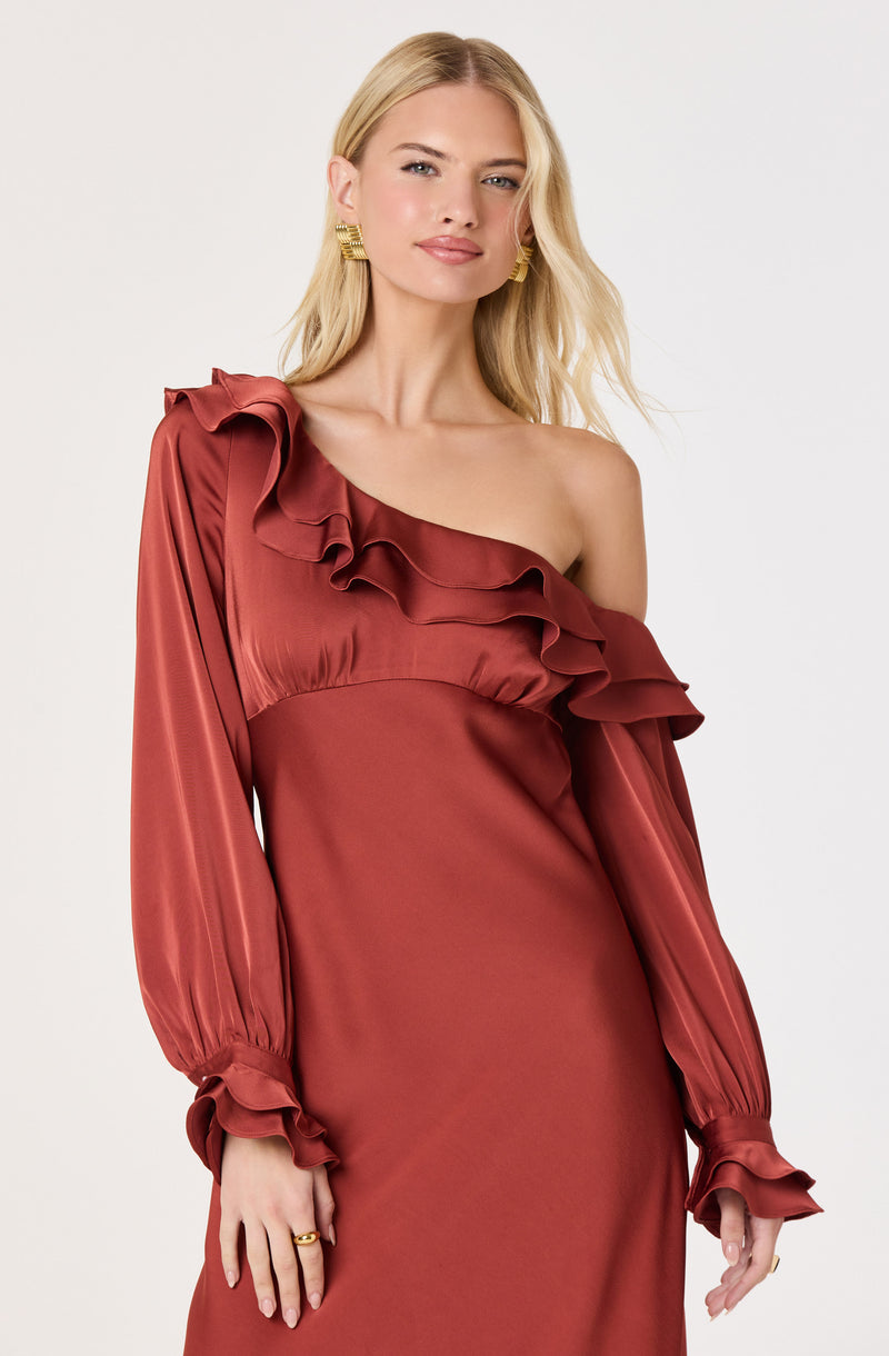 Woman in a rust-colored, one-shoulder satin dress with ruffle details and long, puffed sleeves.