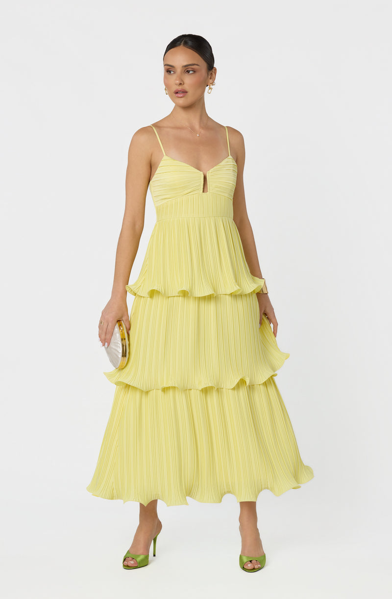 Woman wearing a yellow pleated tiered dress with spaghetti straps and a front keyhole detail.