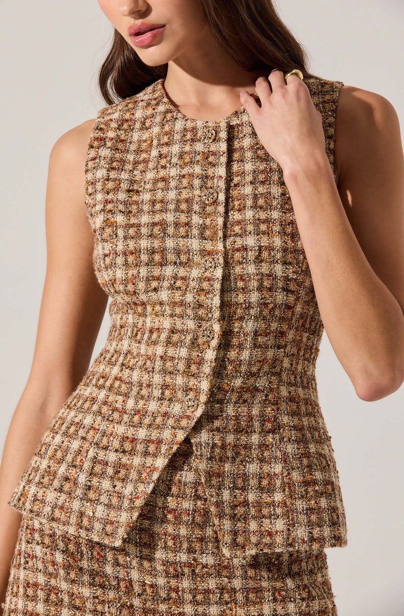 A woman is wearing a sleeveless, fitted dress or top made of textured, tweed-like fabric in a plaid pattern with shades of brown, beige, and reddish tones. The garment features a round neckline and a front button closure that runs down the center.